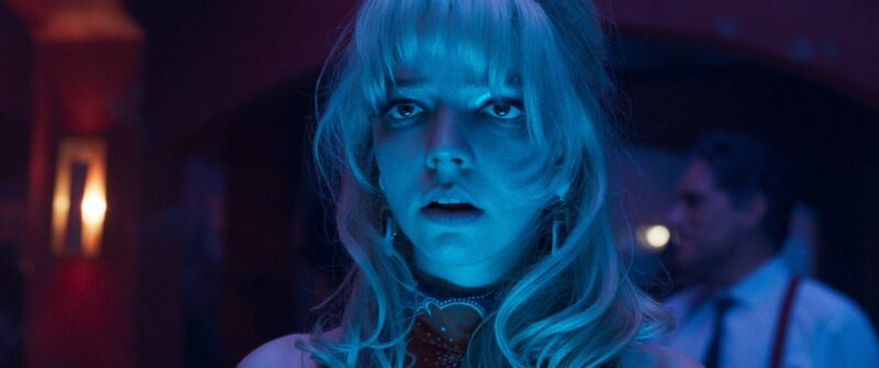 Woman standing with blue tinted light on her. Man in the background